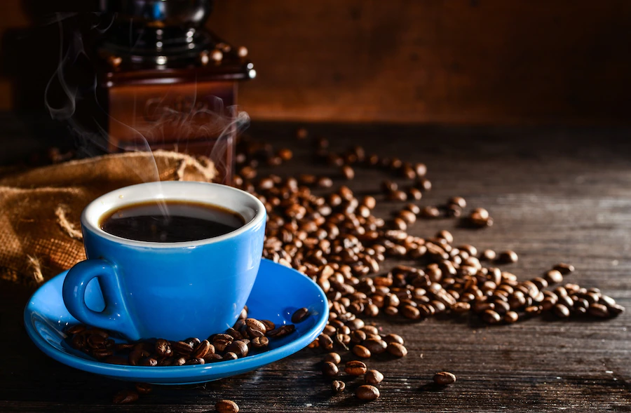 cup-coffee-with-coffee-beans-grinder-background_1112-430